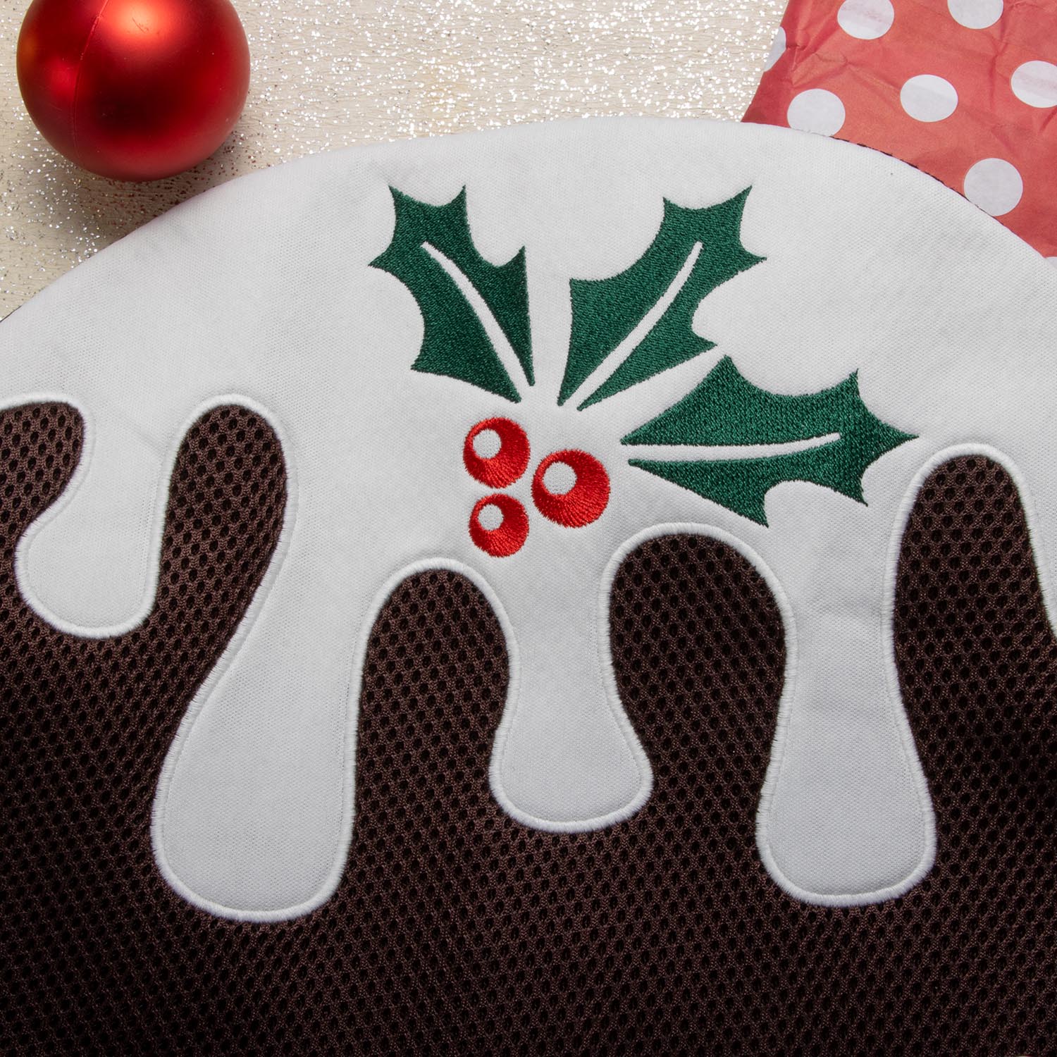 A close-up detail shot of the pudding washbag, showing the texture of the brown mesh fabric and the white 'icing' appliqué.